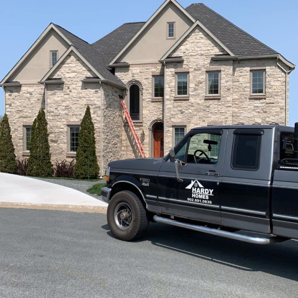 Hardy Homes truck parked in front of a large stone home with new windows