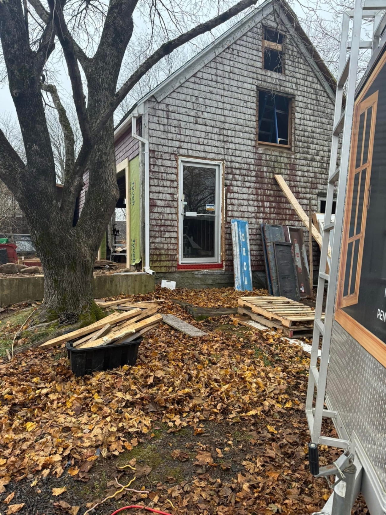 Side of a shingle home mid-renovation with new door and windows
