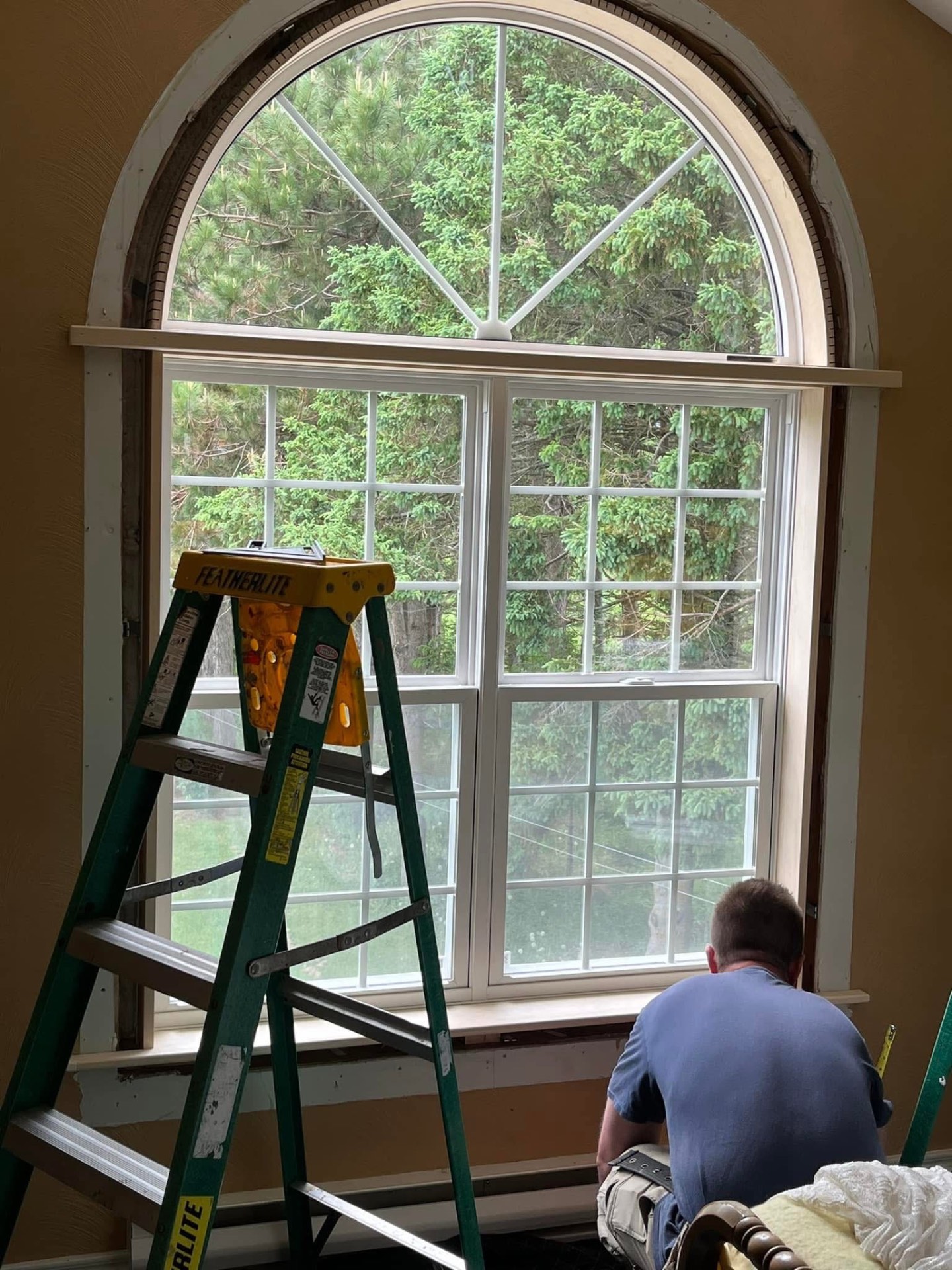 Arched interior window being trimmed after installation